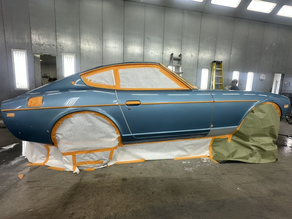 Full side profile of the masked 1977 Datsun 280Z in the paint booth
