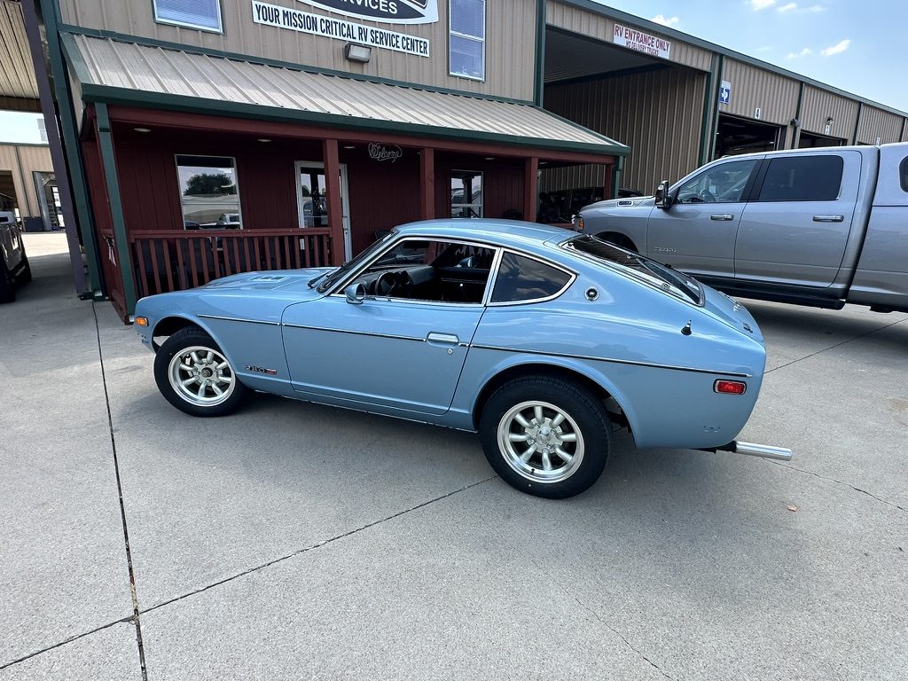Side profile of the restored light-blue 1977 Datsun 280Z outside the Patriots RV Services shop