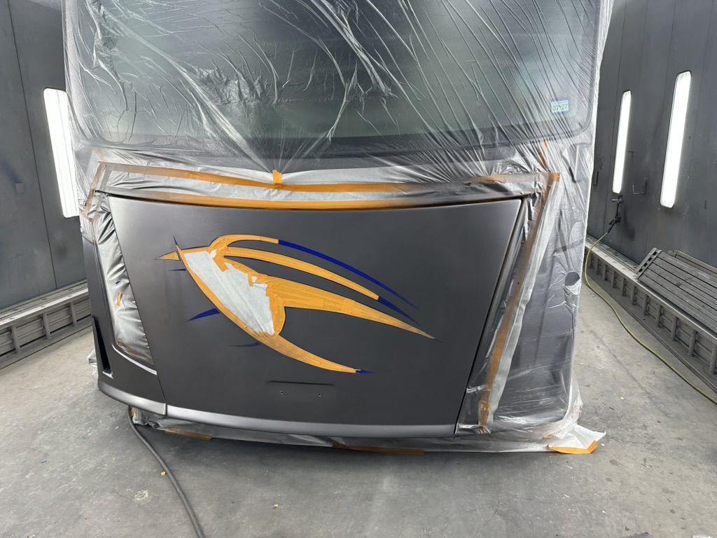 Motorhome front cap masked in the paint booth with graphics taped off before coating