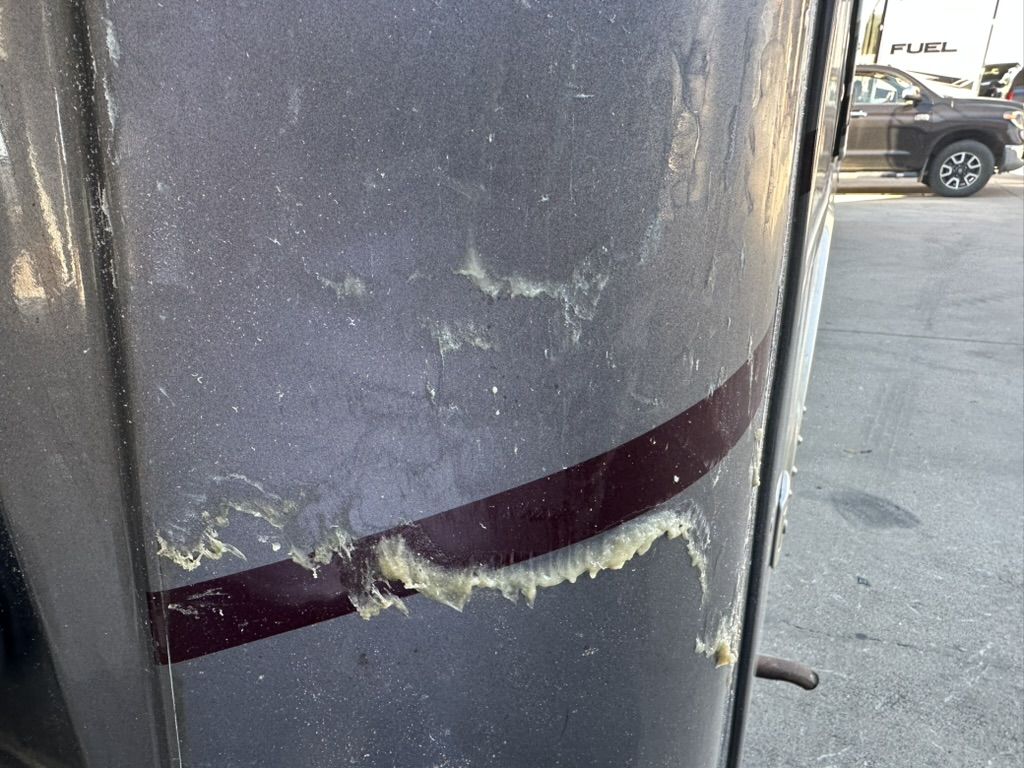 Thick yellowed 3M Diamond Shield adhesive residue left on a motorhome front corner after the film was pulled