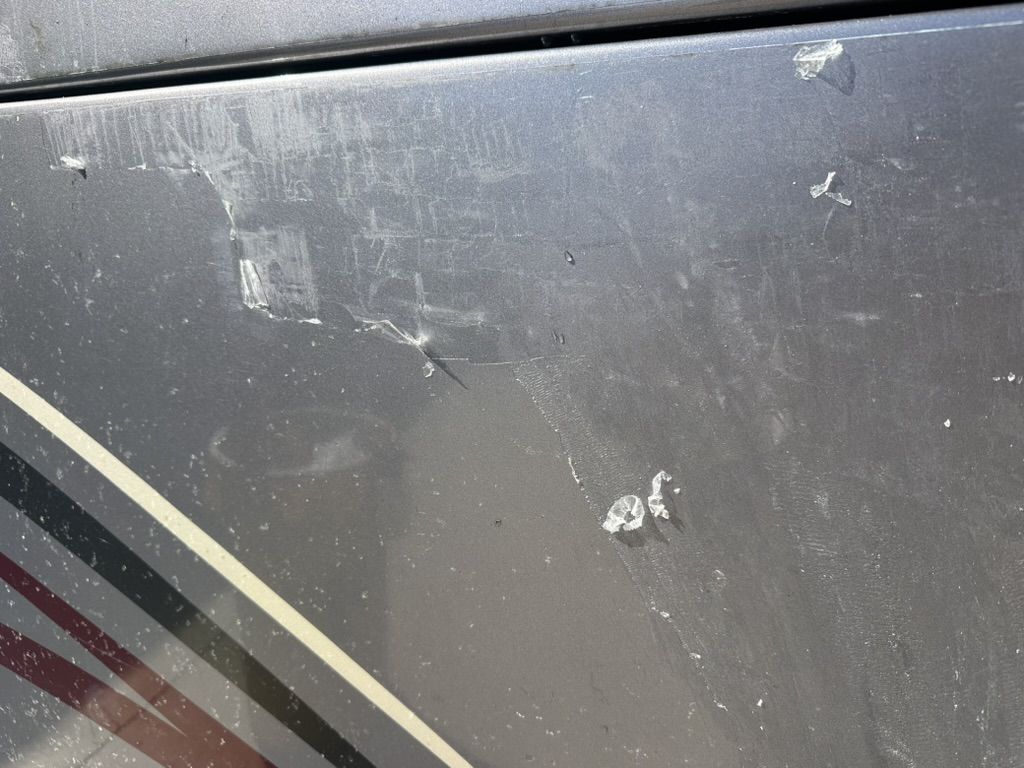 Close-up of torn film pieces and scratches on an RV front cap