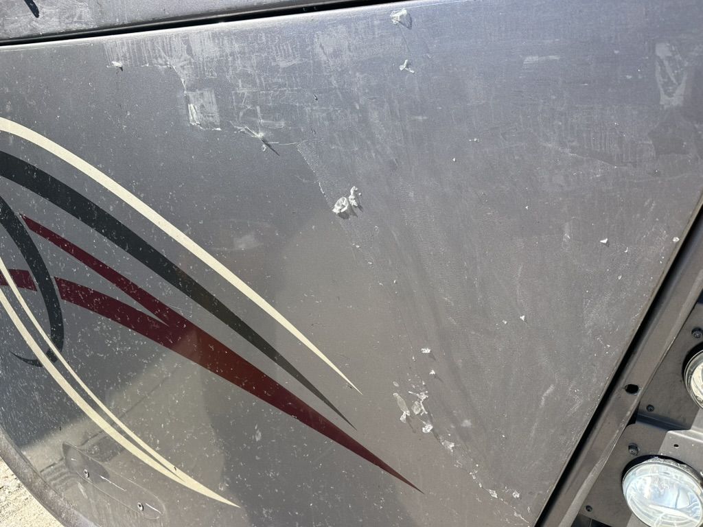 Old protective film lifting and tearing at the edges on a motorhome front cap