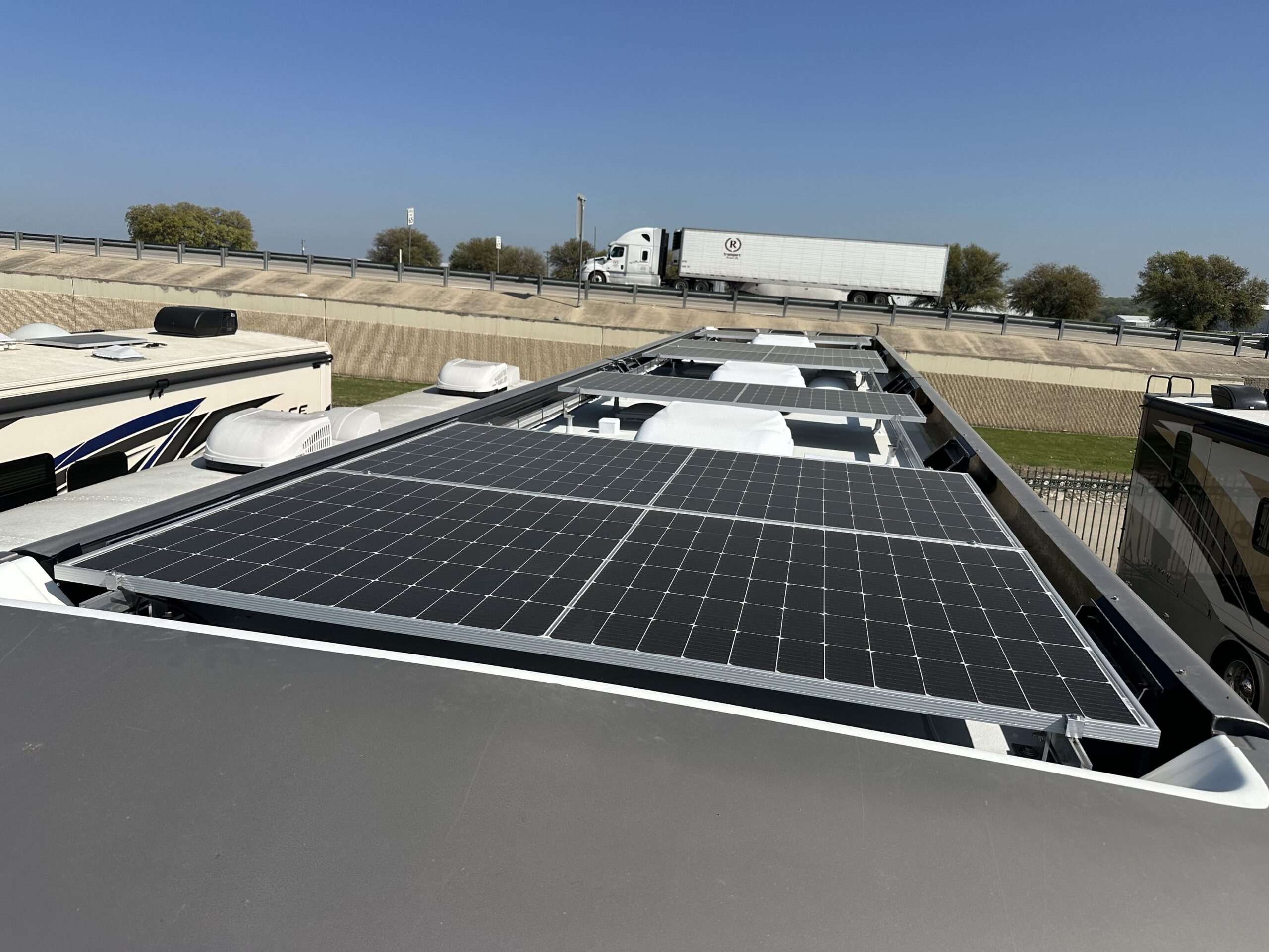Close-up of solar panels installed between AC units on RV roof